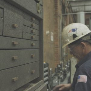 Worker looks through drawers, brandishing American flag and Patriots logo.