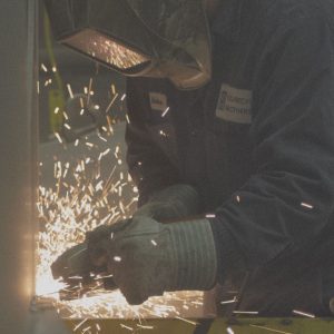 Employee wears safety mask while working with fire.