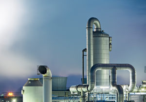 A modern industrial plant with large silver pipelines and structures, against a dusky sky, showcasing advanced energy or manufacturing infrastructure.