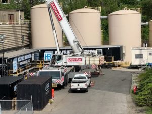 A crane from Barnhart Crane and Rigging in action at Helfrich Brothers Boiler Works, surrounded by trailers and tanks on-site.
