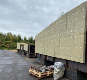 Large metal structures covered with insulation material, lined up outdoors on an overcast day.