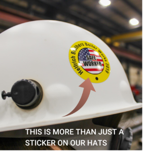 White hard hat with a Helfrich Brothers Boiler Works 2019 Safe Worker sticker, emphasizing safety with the text “MORE THAN JUST A STICKER ON OUR HATS”.