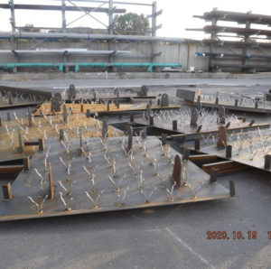 Metal slabs with welded anchors arranged outdoors in an industrial storage area, date stamped 2020.10.19.
