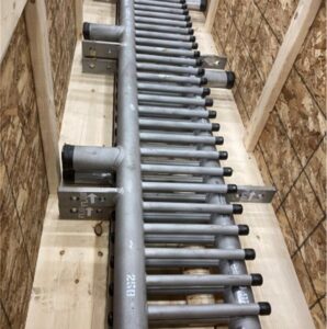 A metal industrial component with multiple tubes secured in a wooden crate, ready for shipping or installation.